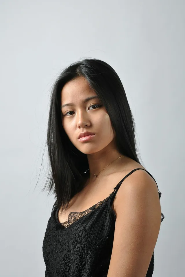 A woman in a black camisole against a pale grey backdrop (illustrative)